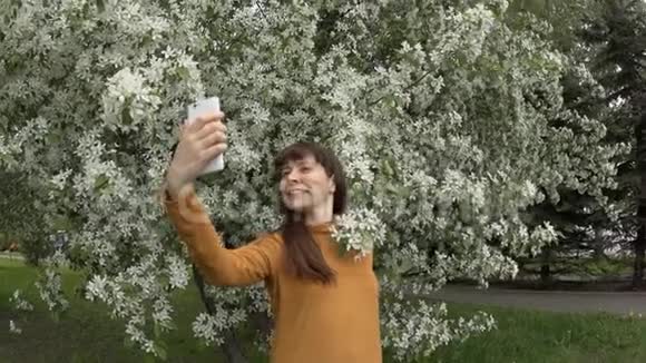 一位年轻女子慢镜头在一棵盛开的苹果树旁边自画像视频的预览图