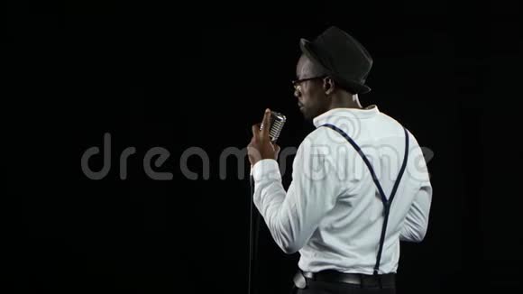 歌手从后面的视图唱成复古麦克风并在它附近跳舞黑色背景关门视频的预览图