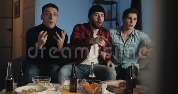 三个朋友在家看电视上的足球赛为最好的足球队加油感情男性球迷庆祝胜利视频的预览图