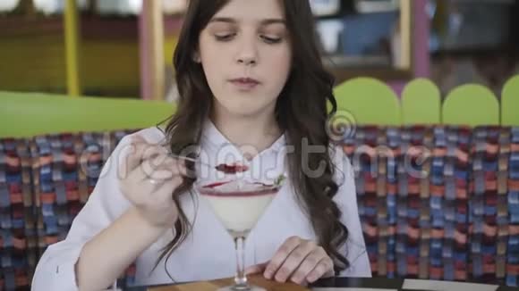 漂亮的女孩微笑着在咖啡馆里吃美味的甜点4K视频的预览图