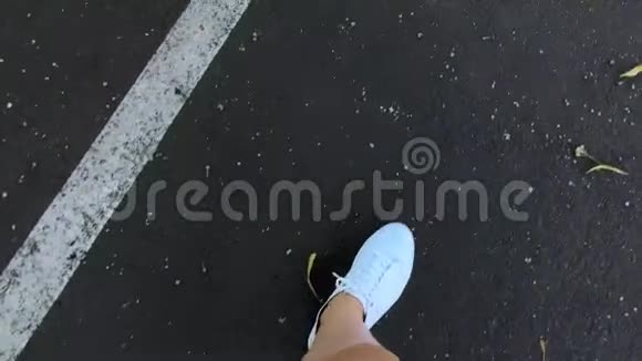 穿着白色运动鞋的女人的腿一个女人正沿着柏油马路走视频的预览图