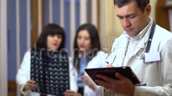一位男医生手里拿着一块药片在背景中医生检查x光视频的预览图