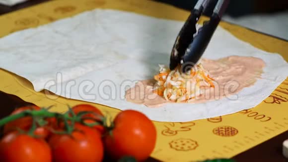 一个女人在厨房准备沙瓦玛把馅放在皮塔面包上视频的预览图