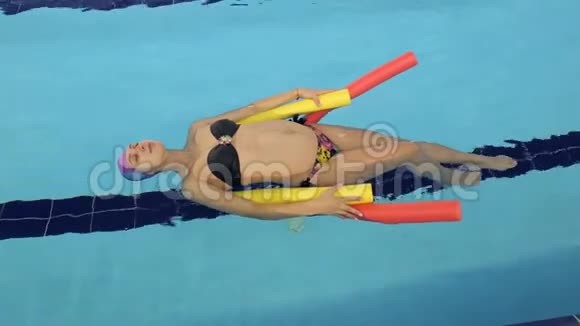 年轻的怀孕女孩躺在游泳池里的水上视频的预览图