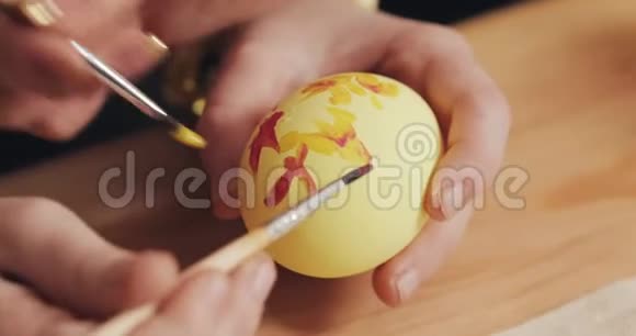 妈妈和女儿用手把复活节彩蛋用颜色和刷子贴紧五颜六色的复活节彩蛋筹备工作视频的预览图