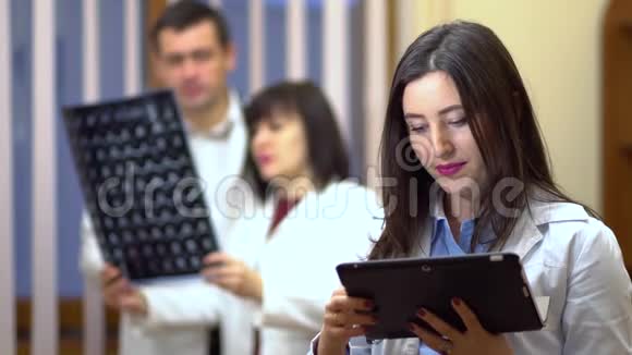 一位女医生手里拿着一块药片在背景中医生检查x光视频的预览图