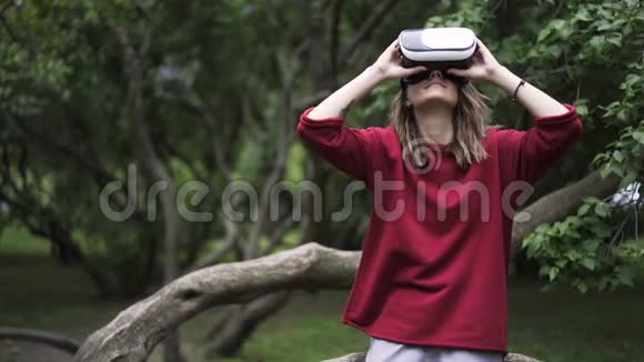 穿红衣服的女人在公园里戴着VR眼镜关门视频的预览图