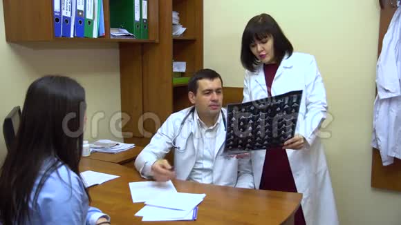 一个年轻的女人坐在医生的办公室里医生看x光照片视频的预览图