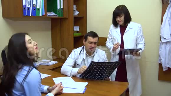 一个年轻的女人坐在医生的办公室里医生看x光照片视频的预览图