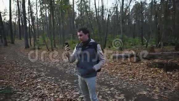 成年男子走在秋天的森林里游客在一个新的地方拍照视频的预览图