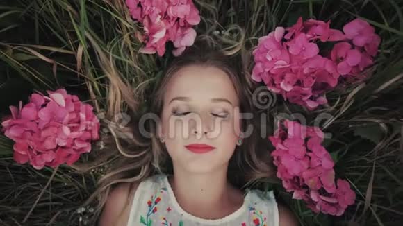 特写一个美丽的女孩躺在一片鲜花盛开的田野上的肖像视频的预览图