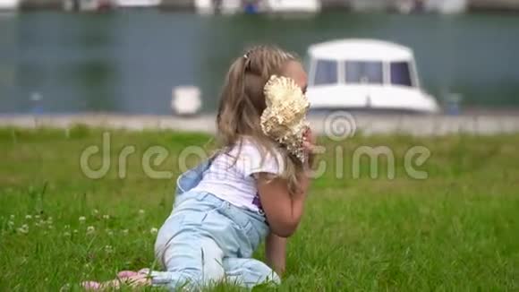 有一点金发女孩听着海浪在一个大公鸡壳女孩坐在码头的草坪上有船视频的预览图