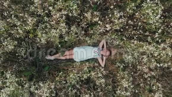 一个女孩躺在花田里放松的空中景色视频的预览图