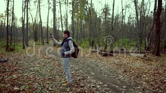 一个人试图在秋天的森林里用他的手机接通视频的预览图