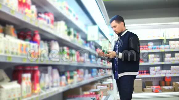 一个中年男子在奶制品部门选择塑料包装的牛奶视频的预览图