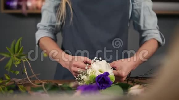 一位花店店员用丝带系着一束花躺在她的桌子上的特写慢动作视频的预览图