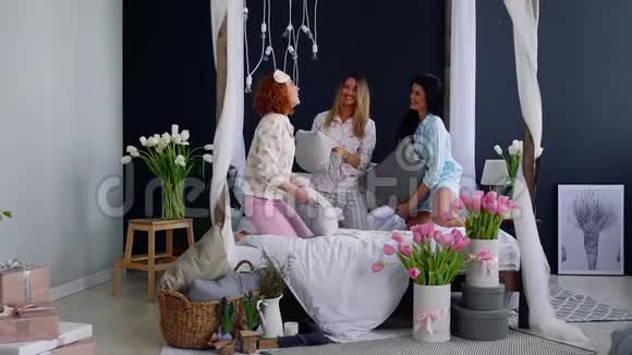 为了庆祝婚礼三个年轻的女人在一个睡衣派对上打枕头美丽的女人笑着视频的预览图