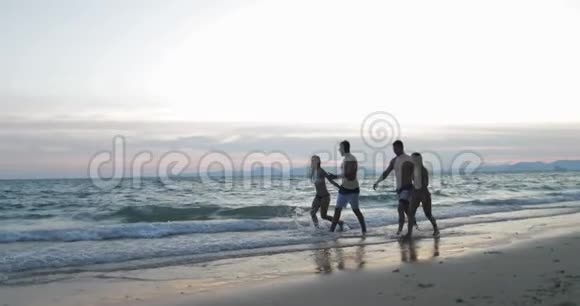 两对幸福的情侣在沙滩上牵手夕阳西下青少年游客在夏日海上度假交流视频的预览图