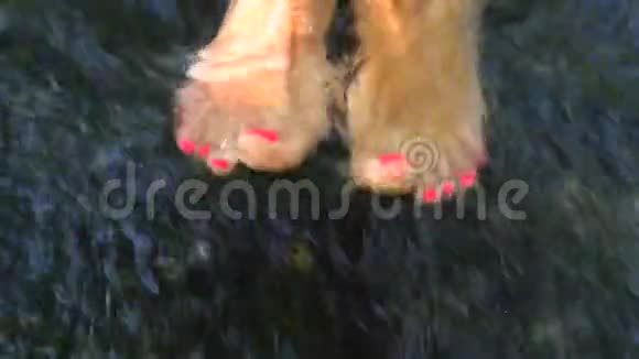 一个赤脚女孩她的脚踩着粉红色的踏板在一条湍急的小溪里在水中嬉戏视频的预览图