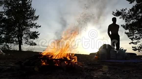 篝火与明亮的火叉和一个人在日落时慢动作视频的预览图