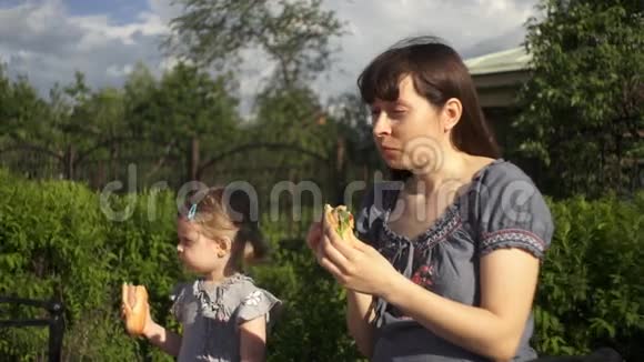 妈妈和小女儿在户外吃热狗视频的预览图