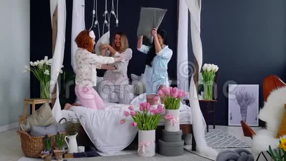 为了庆祝婚礼三个年轻的女人在一个睡衣派对上打枕头美丽的女人笑着视频的预览图