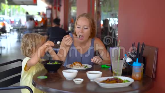 一位年轻女子和她儿子在一家街头咖啡馆里吃中国菜的慢镜头视频的预览图