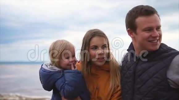 家庭休闲一家四口站在沙滩上天气寒冷多风视频的预览图