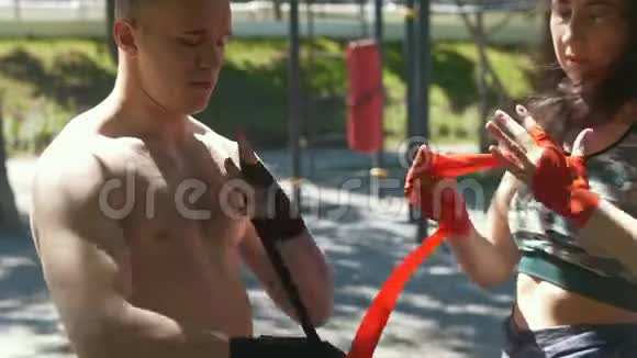 男拳击手包手年轻女子帮他在公园锻炼视频的预览图