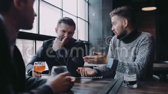 三个朋友一起坐在酒吧里积极讨论他们笑了起来举起酒杯视频的预览图