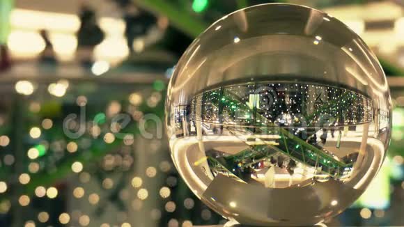顾客在圣诞节和新年装饰购物中心透过玻璃球扭曲的视野视频的预览图