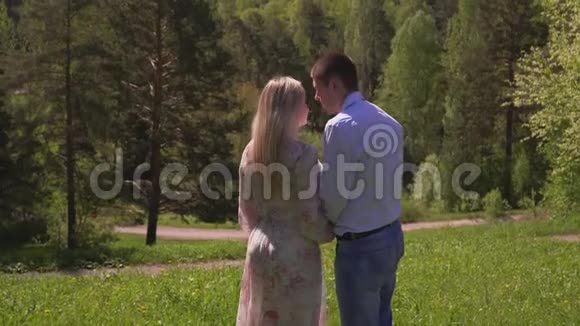 年轻夫妇亲吻花园里的一棵树一个美丽的女孩和那个叫德努西亚的人手牵着一条小路年轻夫妇视频的预览图