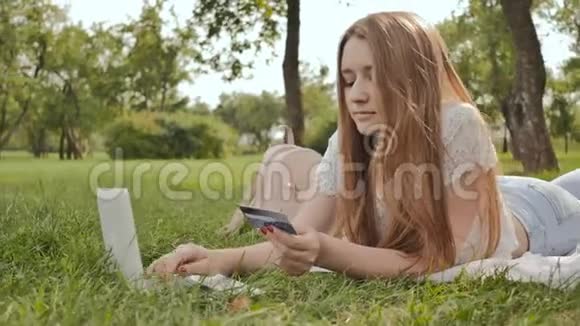 漂亮的年轻女孩用信用卡和笔记本电脑在网上购物视频的预览图