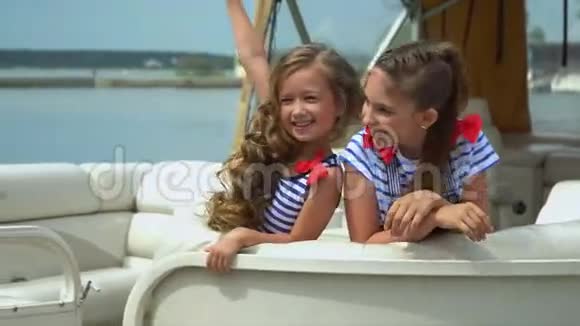 小女孩坐在游艇上可爱的女孩为坐在游艇上的相机摆姿势视频的预览图