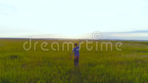 快乐的孩子在绿草的背景下在橙色的阳光下玩玩具飞机视频的预览图