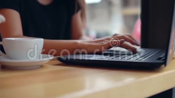 在咖啡休息期间女士的手在笔记本电脑键盘上打字的特写镜头白色杯子视频的预览图