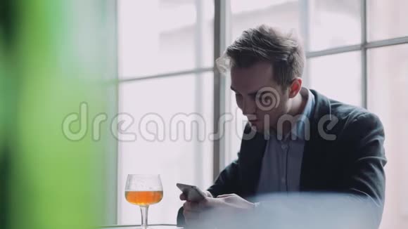 迷人的年轻人独自坐在酒吧里用手机拍照上网喝一口啤酒视频的预览图