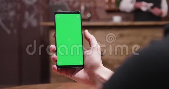 在手机上滚动着绿色屏幕的人视频的预览图