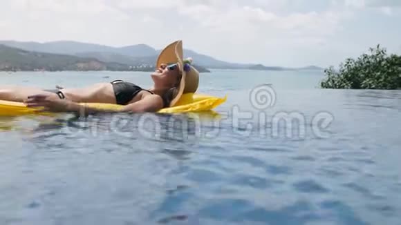 快乐的女人在游泳池里的黄色充气床垫上放松视频的预览图