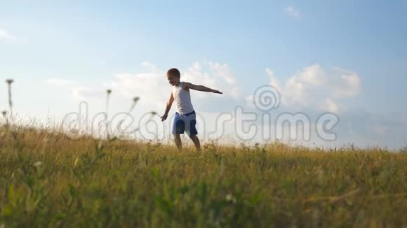 阳光明媚的一天小男孩举起双手在草地上奔跑儿童在户外草坪慢跑快乐视频的预览图