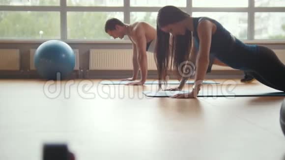 健身房健身男女在健身房一起做俯卧撑家庭健身视频的预览图