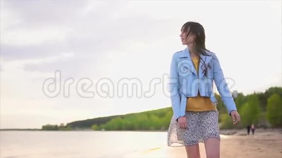 一位年轻女子沿着河边的海滩漫步靠近森林视频的预览图