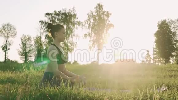 日出时在莲花位置的漂亮女孩健康的生活方式和瑜伽理念视频的预览图