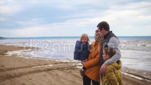 家庭休闲一家四口站在沙滩上天气寒冷多风视频的预览图