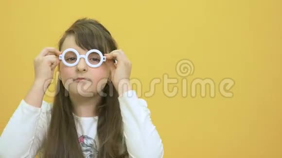 黄色背景上戴塑料眼镜的可爱小女孩视频的预览图