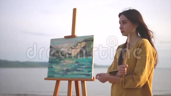 浪漫的女艺术家站在她的平静生活旁边的大海或河流视频的预览图