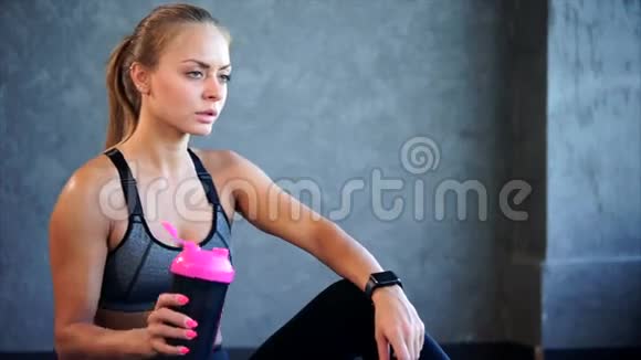 穿运动服的漂亮女孩在健身房锻炼后喝水视频的预览图