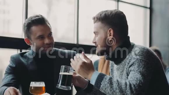 年轻英俊的男性朋友在酒吧里积极讨论一边喝啤酒一边吃薯片非正式视频的预览图