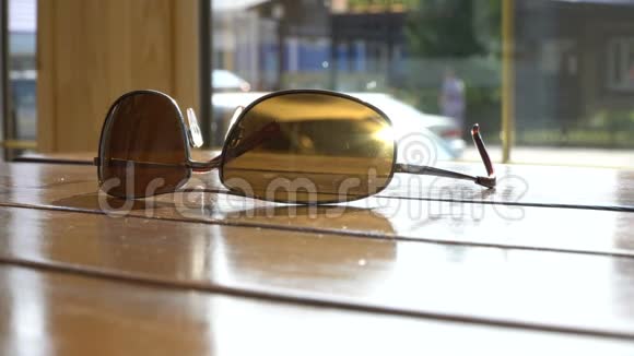 时尚的太阳镜躺在咖啡馆的桌子上阳光明媚的夏季街道背景4k视频的预览图