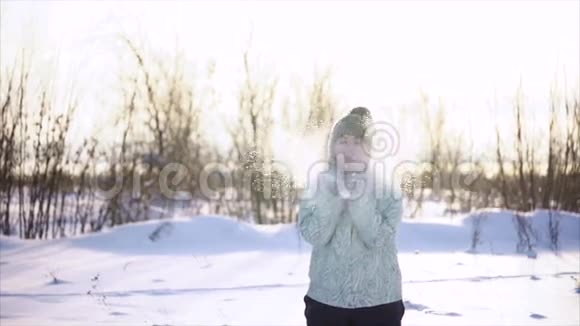 在冬天的一天女人和雪一起玩她用手吹雪视频的预览图